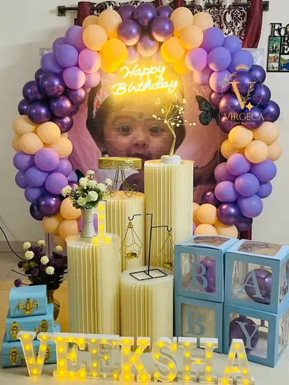 A personalized first birthday setup featuring a large photo of the birthday girl in the center of the balloon arch.