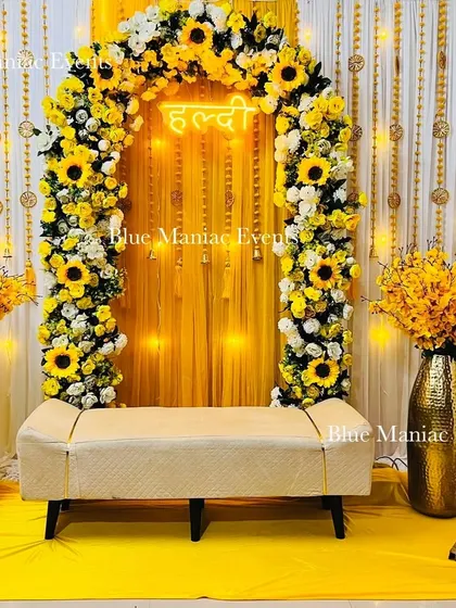 We bring the sunshine to your Haldi ceremony with this cheerful sunflower-themed decor. The setup includes a full floral arch, a bright yellow backdrop with a 'Haldi' neon sign, and matching floral vases, creating a perfect photo opportunity.