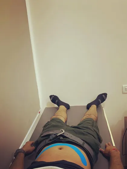 A client lies on a treatment table with kinesio tape applied to their abdomen. This technique can help engage the core muscles, providing stability to the lower back.
