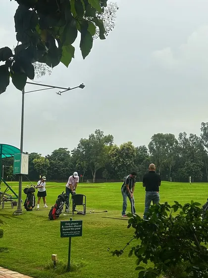 A view from the side of the range shows golfers practicing under the open sky. Our facility offers plenty of space to find your rhythm.