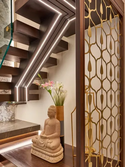 We love to create beautiful moments in transitional spaces. Here, the area under the staircase is transformed with a Buddha statue, elegant vases, and integrated lighting along the steps and handrail.