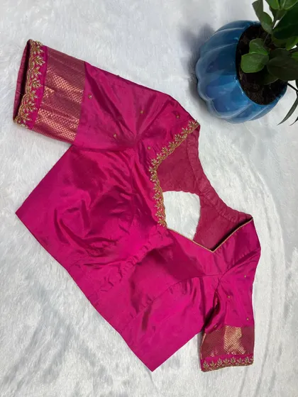 A hot pink blouse with minimal gold embroidery along the neckline and sleeves.