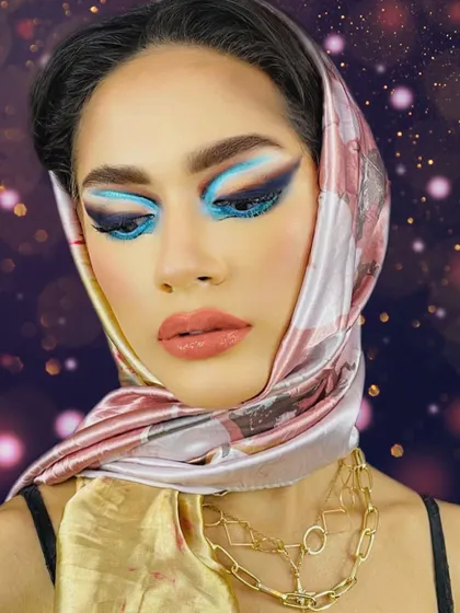 Bringing back the vibe of the 1950s. This look combines a vintage-style headscarf with a modern, bold blue graphic eye, creating a unique fusion of eras.