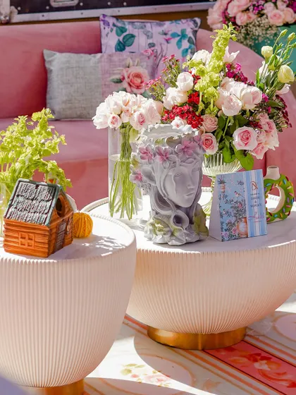 A beautifully styled coffee table with a mix of floral arrangements and decorative objects, including a classical-style bust. The combination of elements creates a sophisticated and romantic vignette.