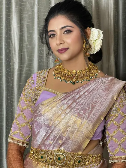 A smiling portrait of the bride, her makeup enhancing her features while complementing the soft purple and gold of her attire.