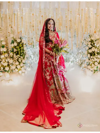 A full-length shot of the bride in her red lehenga, her long veil creating a dramatic and beautiful effect.