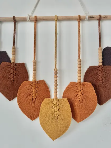 The leaves are hung from a wooden dowel to create a simple and elegant wall hanging.