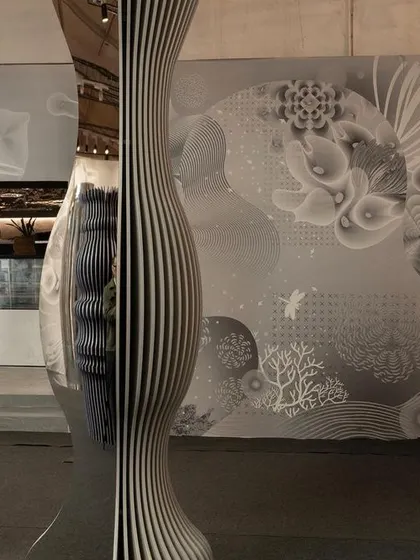A totem from the 'Silver Escapade' installation stands against a backdrop of the Wallpaper of the Year. The combination of sculptural form and graphic surface highlights the play of techniques and finishes used to tell a story of time and transition.