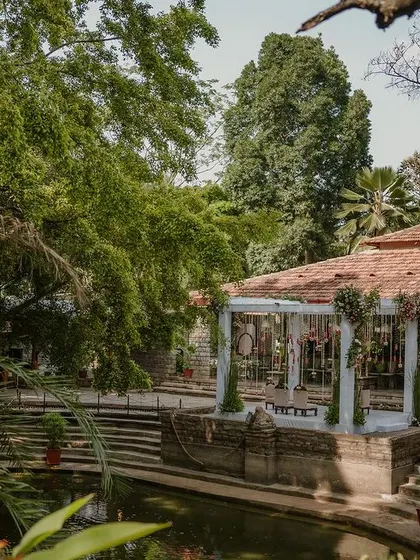 The natural beauty of the venue is enhanced by our decor, with the mandap nestled among ancient trees and stone steps leading down to the water.