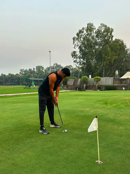 A golfer in all black focuses on his putting stroke on our pristine green.