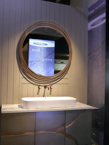 This vanity display combines a round, copper-wire-framed mirror with a sleek white basin and a cabinet with flowing, organic lines.