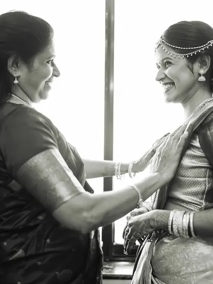A happy black and white photo of a mother and daughter sharing a smile as they get ready.
