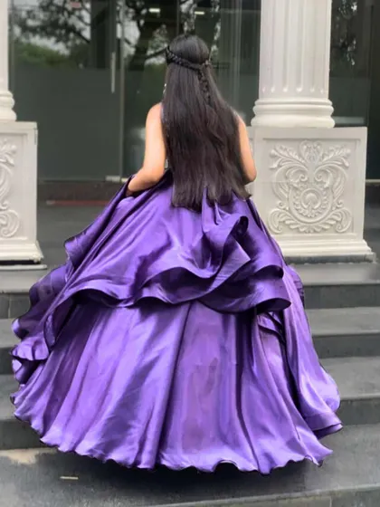 The back of this purple ball gown shows the voluminous, layered tiers of satin that create a dramatic and enchanting silhouette, perfect for a grand entrance.
