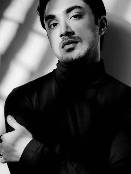 A moody, shadowed portrait of Lakshya Parikh in the black turtleneck.