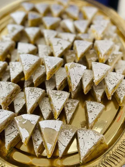 A platter of my signature Dryfruit Sandwich sweets. The layers of nuts and mawa, dusted with powdered sugar, make it a visually stunning and delicious dessert.