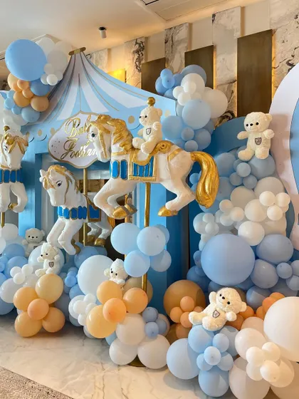 To welcome a baby boy, we designed a beautiful carousel-themed setup with pastel blue and peach balloons, classic carousel horses, and adorable teddy bears.