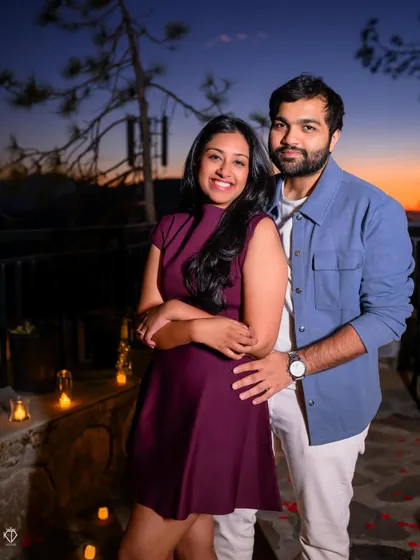 A classic couple portrait after the proposal, smiling happily for the camera against the backdrop of the mountains at dusk.