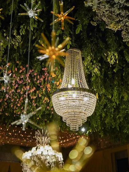 A view of the ceiling, showing the lush greenery, hanging stars, and magnificent crystal chandeliers.