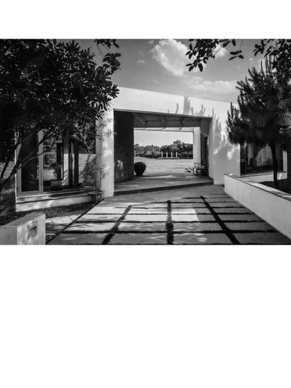 A framed view through an opening in the House of Axes, looking out onto a landscaped court. The architecture is designed to create deliberate perspectives, guiding the eye and creating a sequence of experiences as one moves through the property.