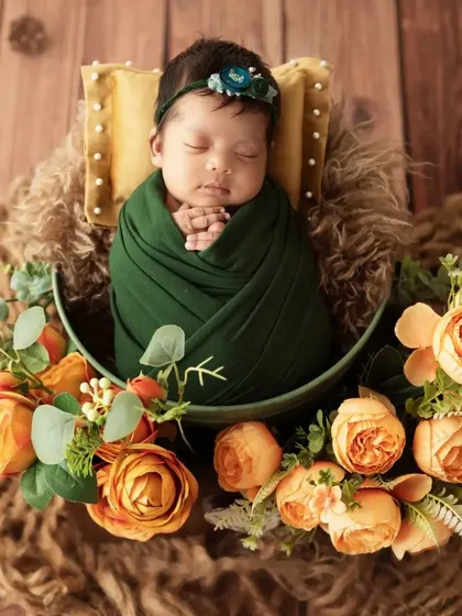 An overhead view of the baby in the green wrap, with her hands clasped together.
