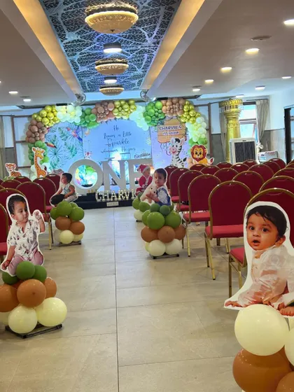 A wide view of a jungle themed event hall, with personalized cutouts of the birthday child placed along the aisle leading to the main stage.