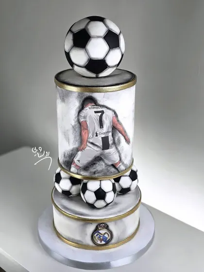 An extravagant, two-tiered football cake featuring a hand-painted player, realistic footballs, and gold accents for a premium look.