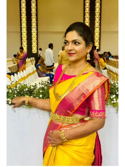 This client looks radiant in her bright yellow and pink saree, paired with a custom-designed pink blouse. The blouse features intricate embroidery on the sleeves for a touch of sparkle.