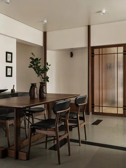 The dining area in Apartment 1005, featuring a custom hardwood table and chairs. The space is separated from the rest of the apartment by a translucent screen, creating an intimate setting for family meals.