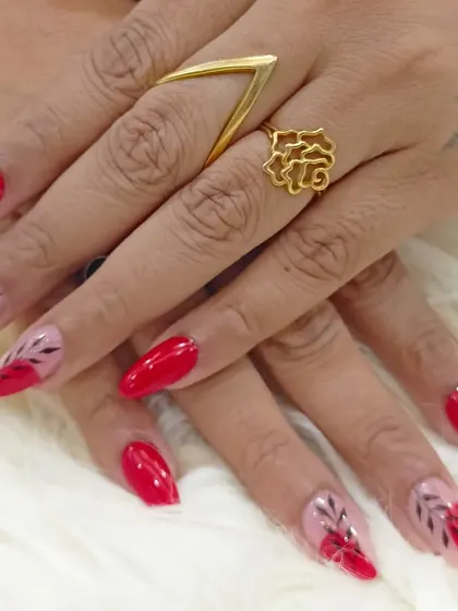 A bold and beautiful set featuring glossy red stiletto nails. Accent nails have a sheer base with hand-painted black leaf silhouettes for a modern, artistic touch.