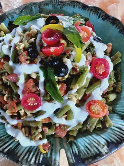 A healthy bean salad with tomatoes and olives, finished with a creamy yogurt dressing.