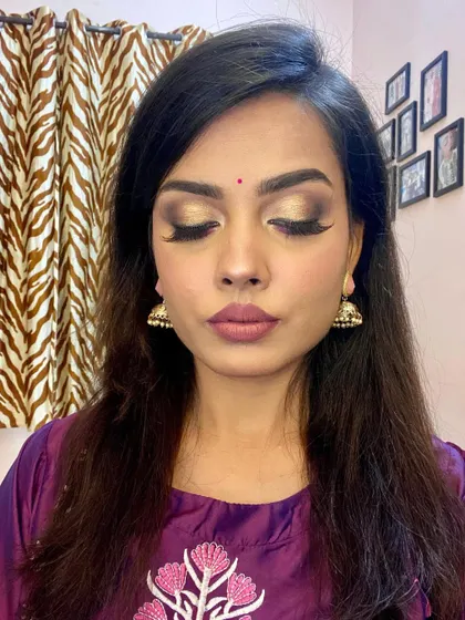 The eyes closed, showing the full effect of the golden smokey eye. The blending is seamless, creating a sophisticated look that is perfect for any festive occasion.