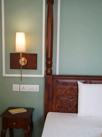 A duplicate of image 197, focusing on the fine details of the carved bedpost and elegant wall lighting.