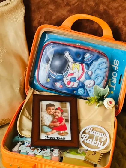 A personalized Rakhi suitcase hamper featuring a photo of siblings, making it a memorable and heartfelt gift for a child.