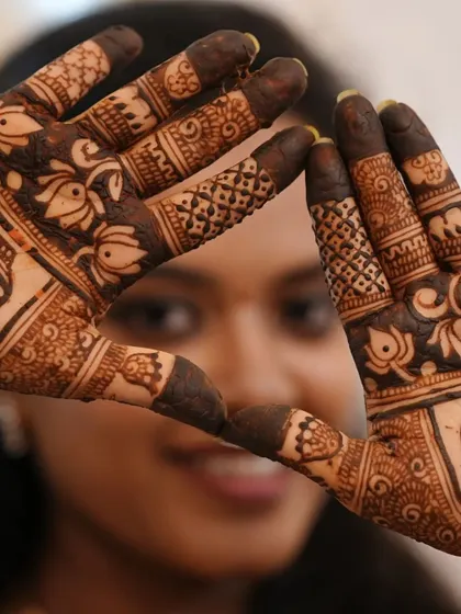 A creative heart-shaped pose, framing the client's face with her intricately designed hands. A perfect shot for any mehendi lover.