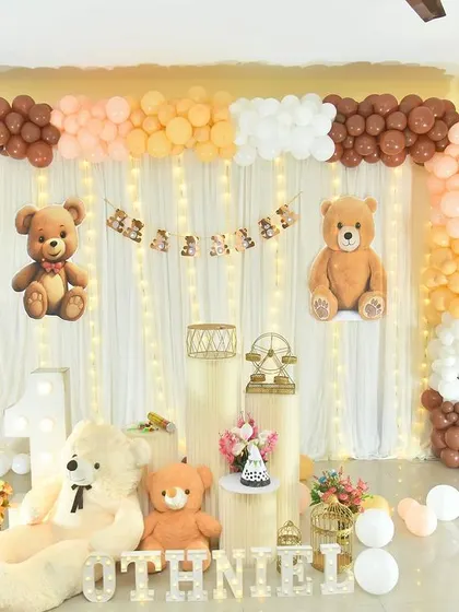 A cozy teddy bear theme with a backdrop of fairy lights and a warm, earthy-toned balloon arch.