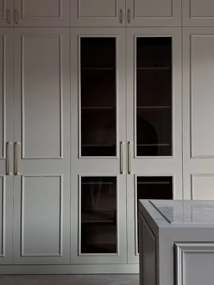 A beautifully lit shot of the finished wardrobes, showcasing the smoked glass panels and the sophisticated, muted color palette of the closet.