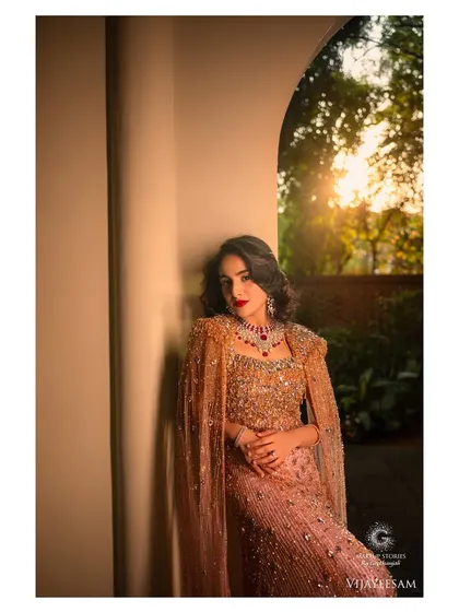 An artistic shot capturing the golden hour light. The makeup is warm and glowing, with a bold red lip that stands out beautifully against the soft, romantic background.