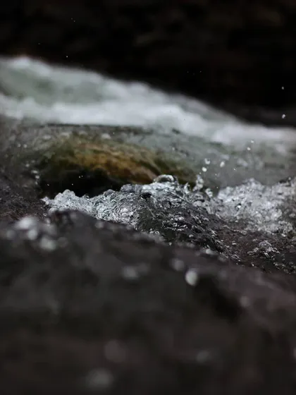 A close up shot of water flowing over rocks. The camera freezes the motion of the bubbles and splashes, reminding me that time, like water in a river, is always flowing away.