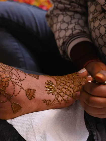 A close-up shot of me applying a delicate floral and net pattern on a bride's foot. Every detail is carefully drawn to ensure a perfect finish.