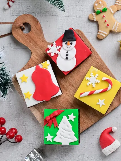 Our Christmas-themed brownie squares are almost too cute to eat. Each one is decorated with a unique design, including a snowman, a bell, a Christmas tree, and a candy cane.