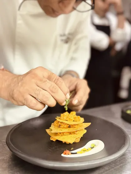 A chef carefully constructs a dish, layering crispy mathri with a savoury filling. This is our playground for new ideas and perfecting the tiny details.