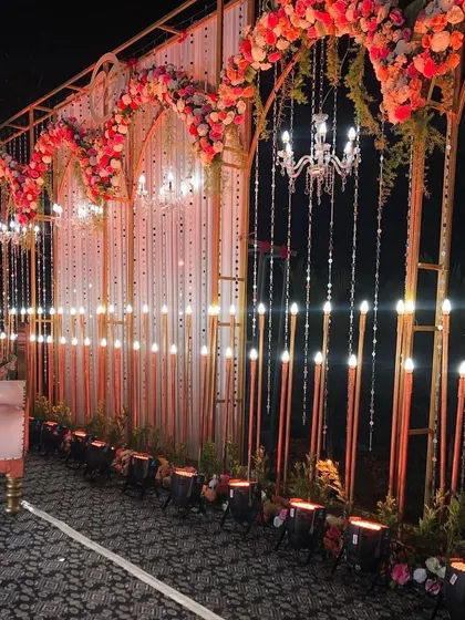 A detailed shot of an ornate reception stage in Lonavala. The design features a golden frame with multiple arches, hanging crystals, and warm lighting for a truly luxurious feel.
