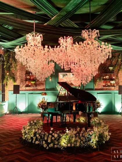 The centerpiece of the glass house reception: a grand piano surrounded by white flowers, set under magnificent crystal chandeliers. This created a focal point of pure elegance and romance.