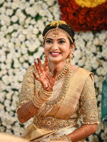 Rakshita waving happily, looking every bit the perfect South Indian bride in her gold Kanjeevaram and traditional jewellery.
