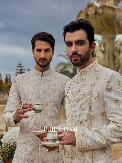 With delicate cups in hand, they embody the spirit of 'Amore'. These two gentlemen wear coordinated but unique ivory sherwanis, showcasing how sophistication can be shared in moments of quiet camaraderie.