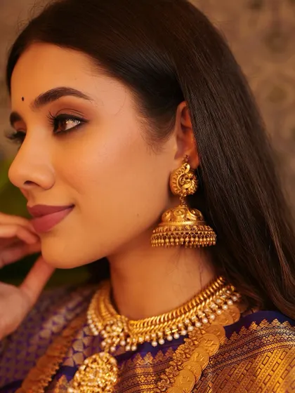 A stunning profile shot that highlights the traditional jhumka earring and the soft, defined eye makeup. My training focuses on creating looks that are beautiful from every angle.