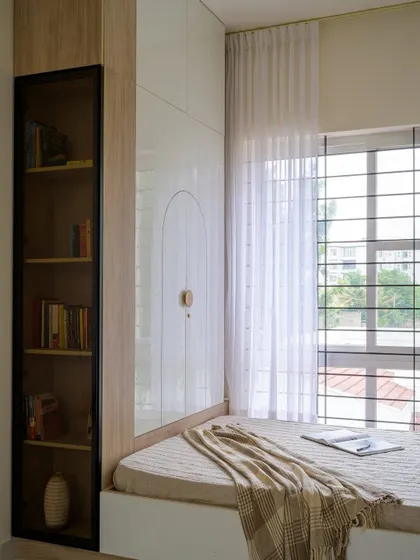 This view shows the full-height wardrobe and a tall, glass-fronted bookshelf, providing extensive storage for a growing child's needs in a bright and organized way.