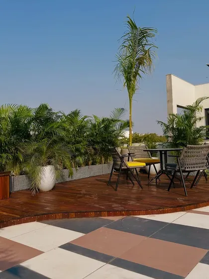 The combination of the wooden deck, patterned stone tiles, and lush planters demonstrates a thoughtful mix of materials and textures.