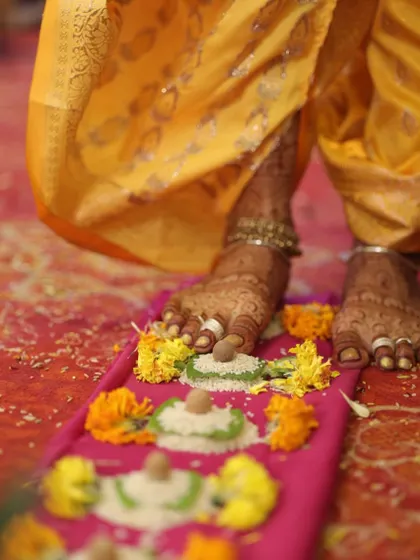 A beautiful moment from a wedding ceremony, capturing the bride's feet adorned with intricate mehendi as she participates in the rituals.