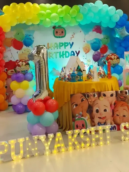 Another angle of the Cocomelon first birthday party, showcasing the colorful balloon pillars, the large number '1' foil balloon, and the character cutouts that bring the theme to life.